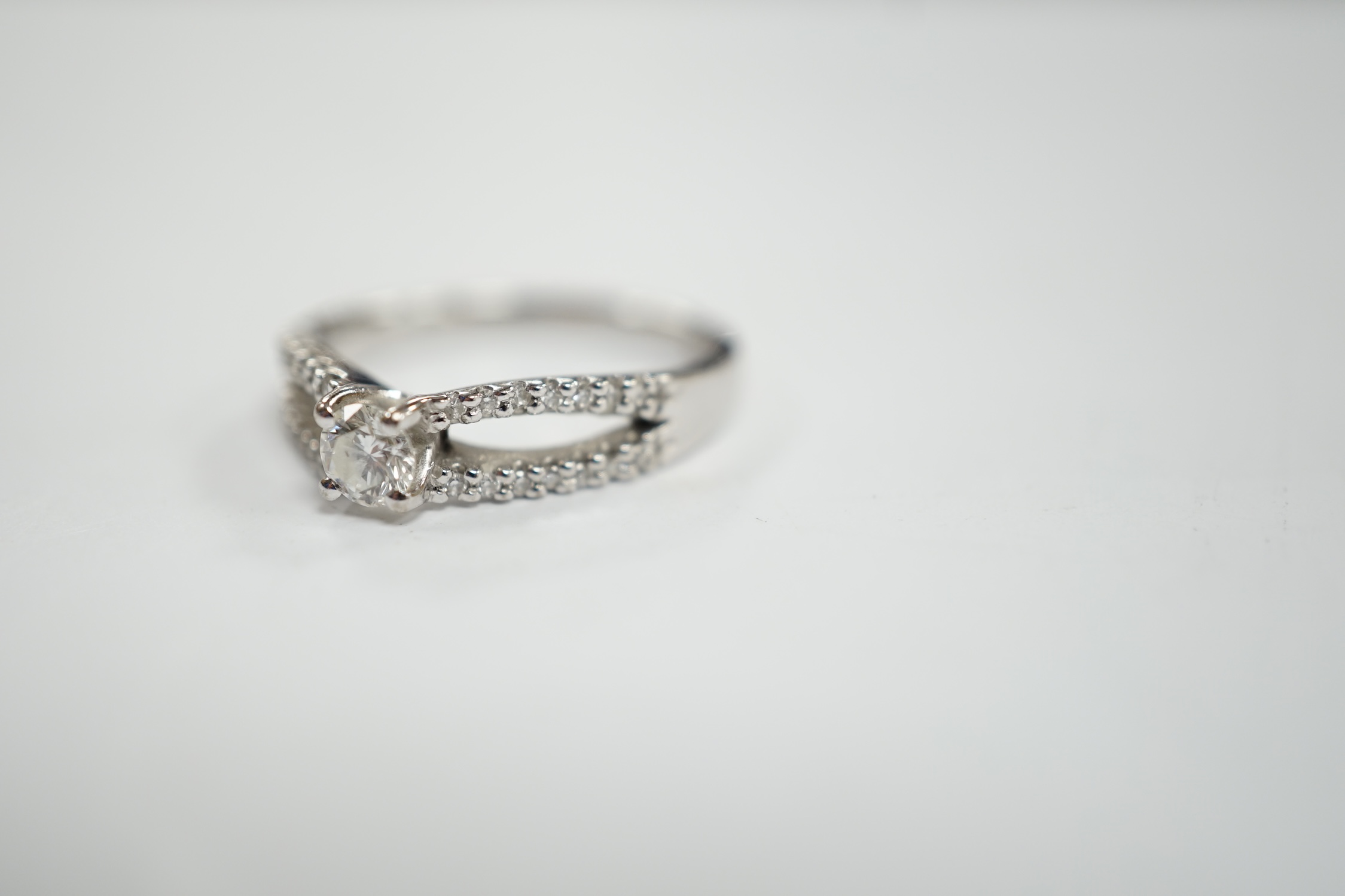 A modern 18ct white gold and single stone diamond set ring, with diamond chip set split shoulders, size O, gross weight 4.2 grams.